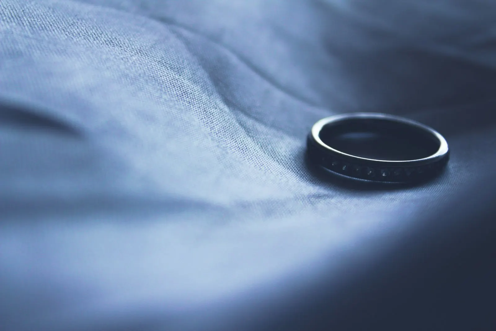 Aliança de casamento com pedras pousada sobre tecido azul